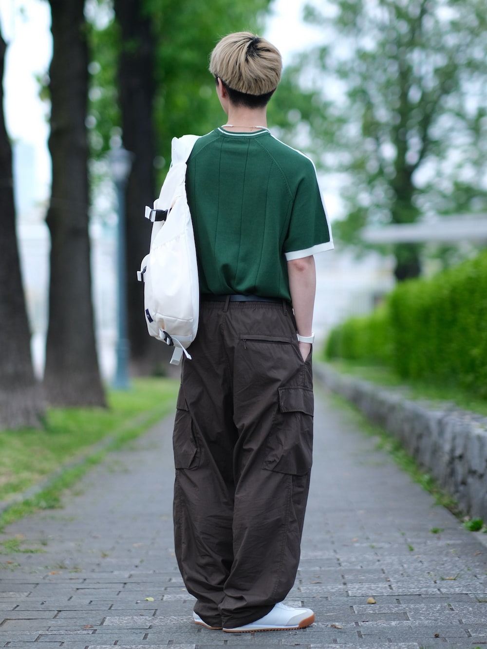 グリーン系のニット/セーター、ブラウン系のカーゴパンツ、ホワイト系のスニーカーを着用したメンズの夏コーディネートの3枚目の写真