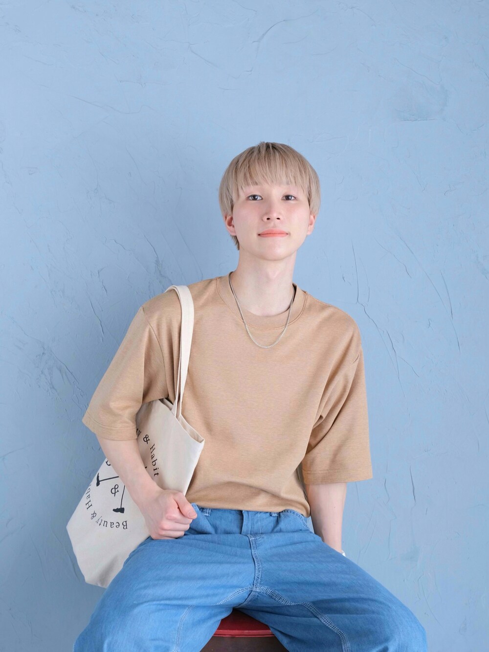 ベージュ系のトートバッグ、イエロー系のスニーカー、ブルー系のデニムパンツを着用したメンズの春コーディネートの2枚目の写真