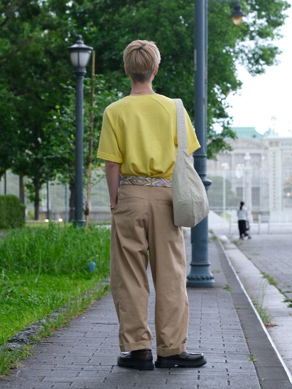 イエロー系のTシャツ/カットソー、ベージュ系のチノパンツ、ホワイト系のショルダーバッグを着用したメンズの夏コーディネートの4枚目の写真