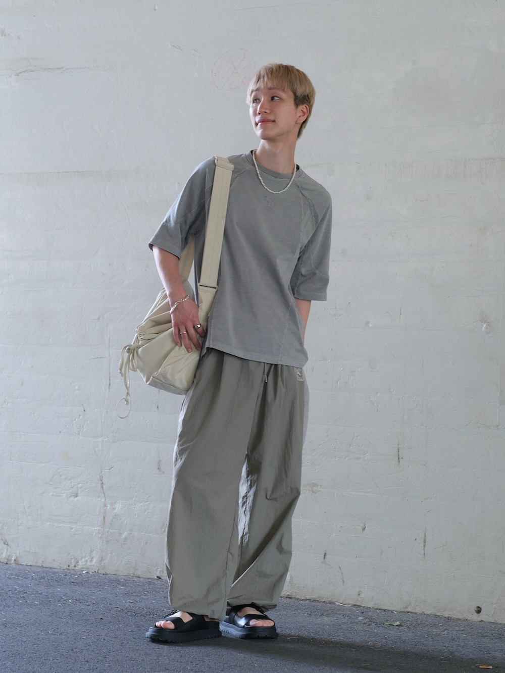 ベージュ系のその他パンツ、グレー系のTシャツ/カットソー、ホワイト系のショルダーバッグを着用したメンズの夏コーディネートの4枚目の写真