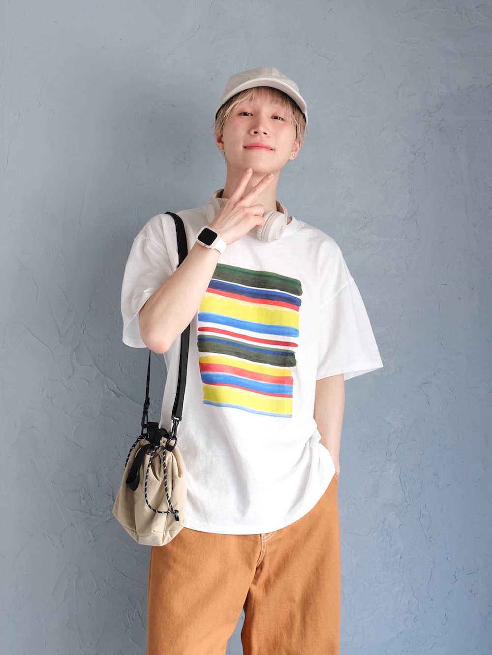 ブラウン系のチノパンツ、ホワイト系のTシャツ/カットソー、ベージュ系のヘッドフォン/イヤホンを着用したメンズの春コーディネートの2枚目の写真