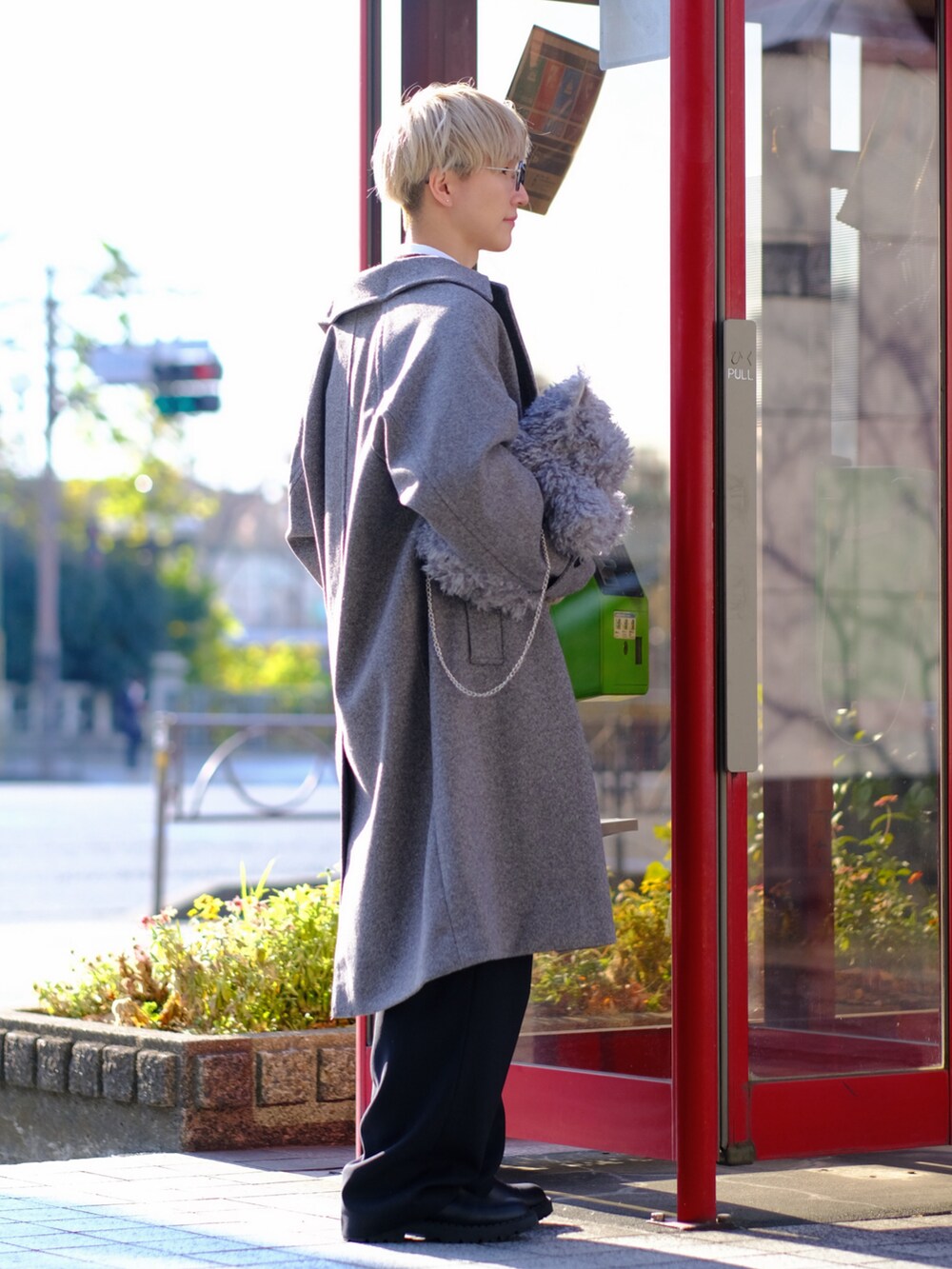 グレー系のショルダーバッグ、グレー系のステンカラーコート、ブラック系のスラックスを着用したメンズの冬コーディネートの4枚目の写真