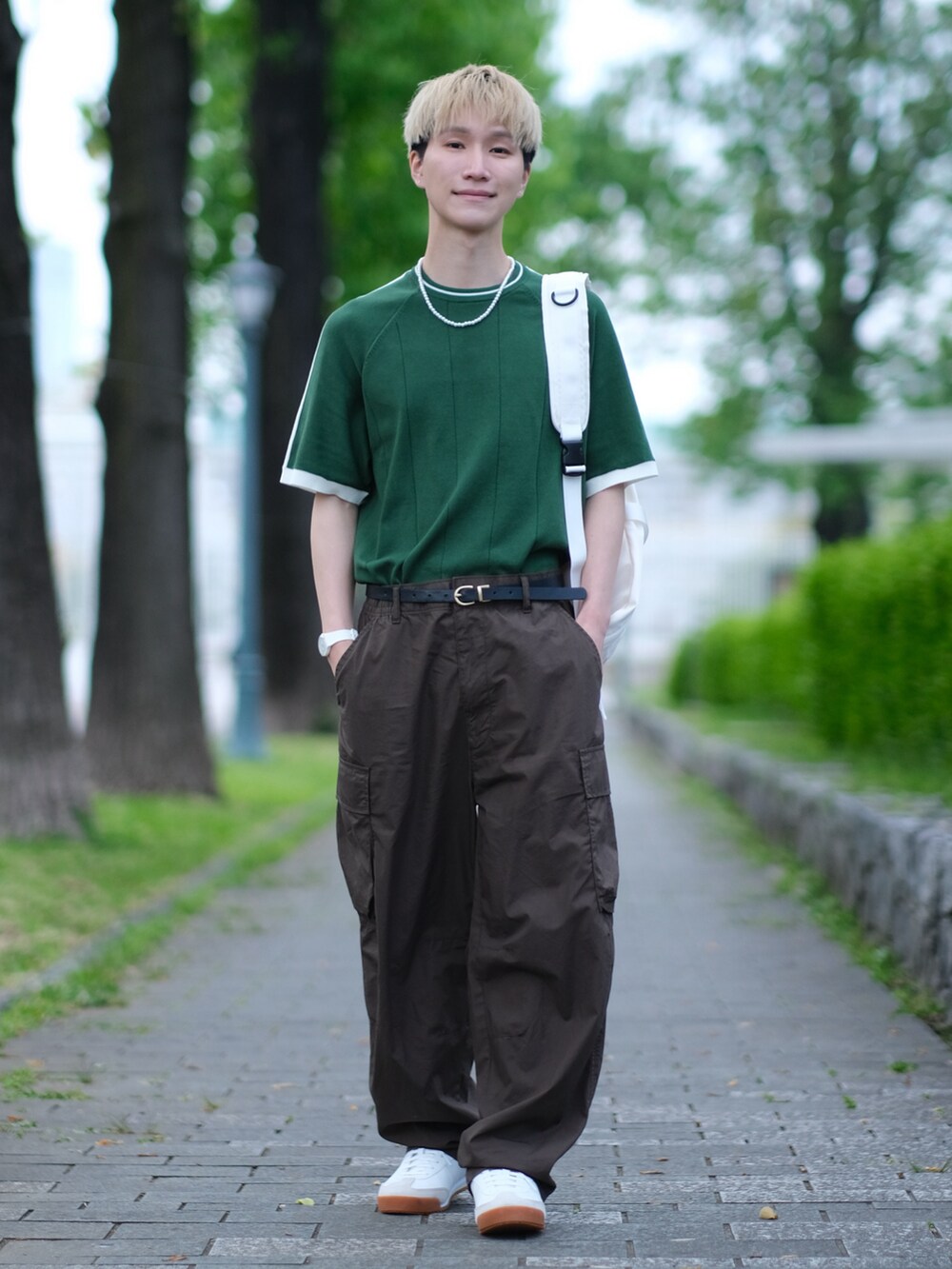 グリーン系のニット/セーター、ブラウン系のカーゴパンツ、ホワイト系のスニーカーを着用したメンズの夏コーディネートの5枚目の写真