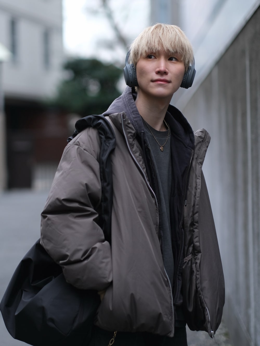 ブラウン系のダウンジャケット/コート、ブラック系のデニムパンツ、ブラック系のショルダーバッグを着用したメンズの冬コーディネートの2枚目の写真