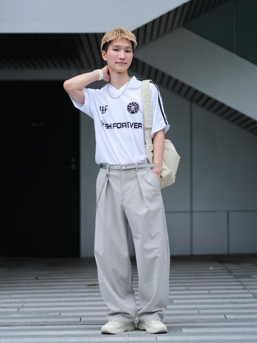 ホワイト系のTシャツ/カットソー、グレー系のスラックス、ホワイト系のスニーカーを着用したメンズの夏コーディネートの3枚目の写真