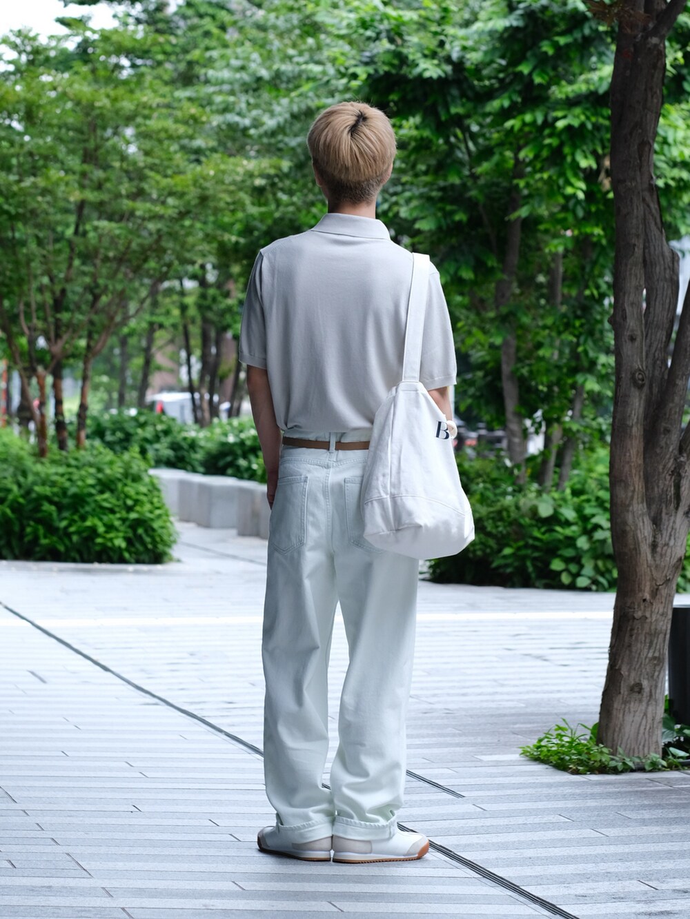 ホワイト系のデニムパンツ、ホワイト系のポロシャツ、ホワイト系のスニーカーを着用したメンズの夏コーディネートの4枚目の写真