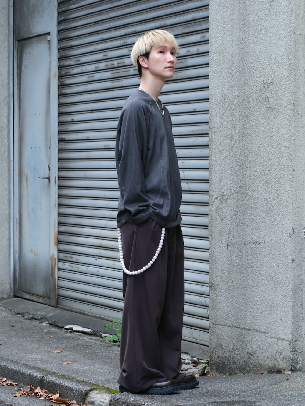 ブラック系のTシャツ/カットソー、ブラウン系のスラックス、ブラウン系のシューズを着用したメンズの夏コーディネートの3枚目の写真