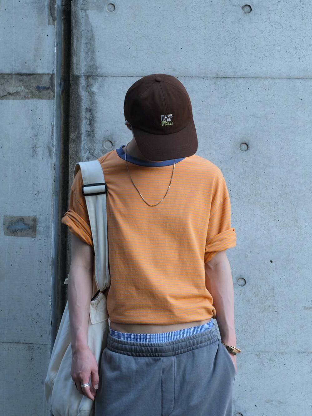 グレー系のスウェットパンツ、オレンジ系のTシャツ/カットソー、ブラウン系のシューズを着用したメンズの春コーディネートの3枚目の写真