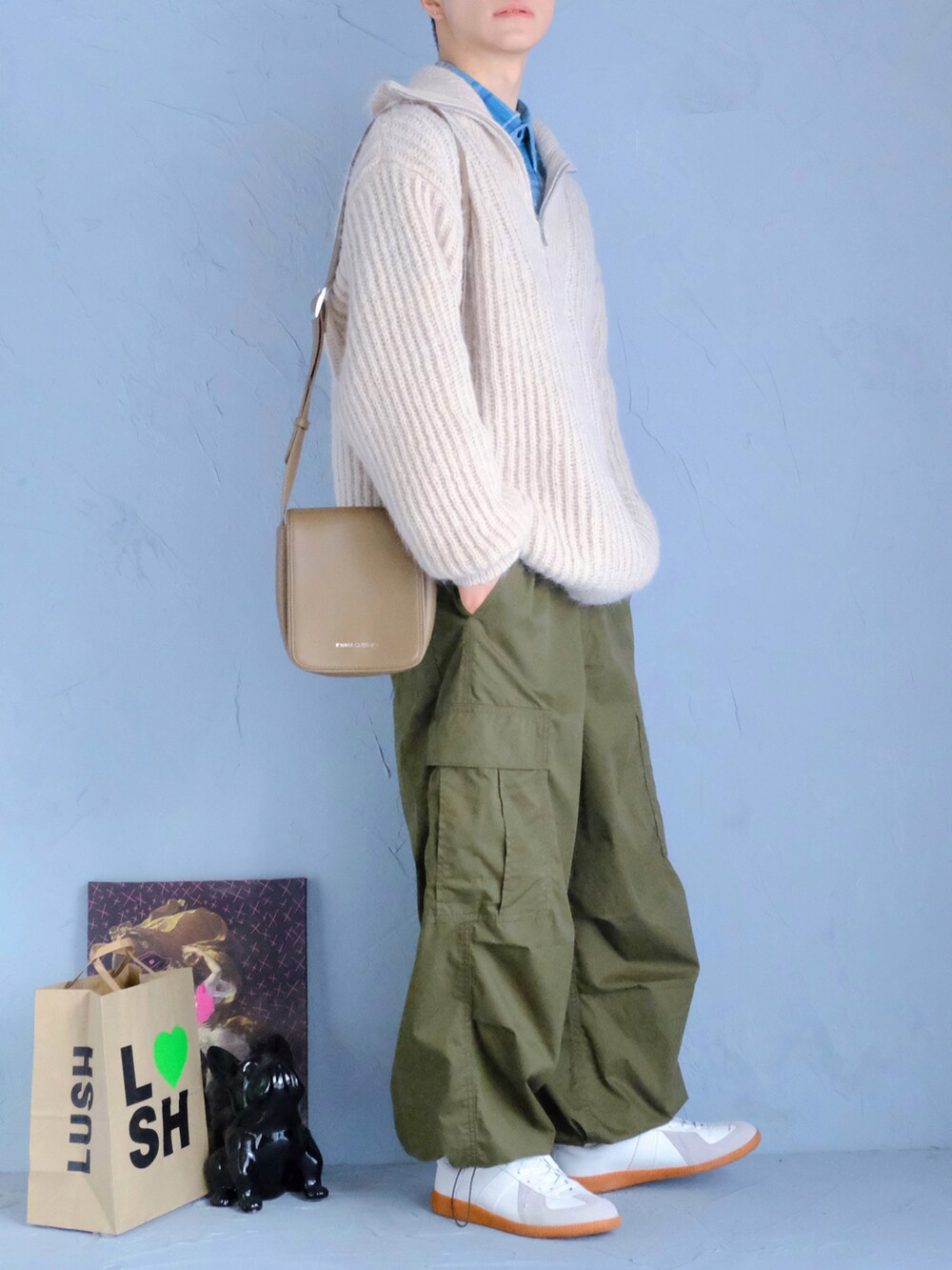 ホワイト系のスニーカー、グリーン系のパンツ、ベージュ系のショルダーバッグを着用したメンズの冬コーディネートの2枚目の写真