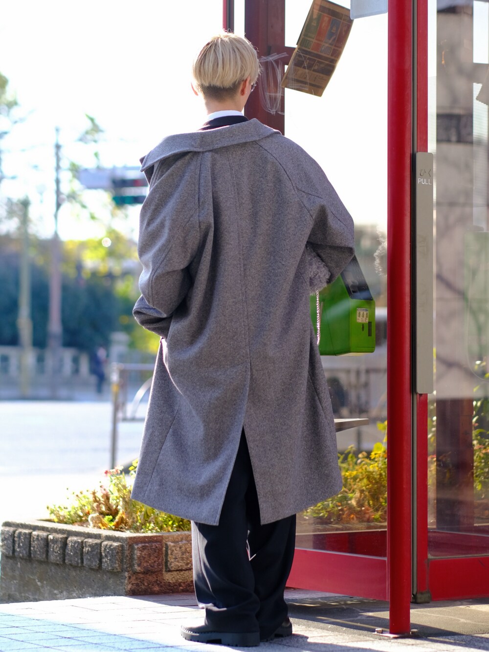 グレー系のショルダーバッグ、グレー系のステンカラーコート、ブラック系のスラックスを着用したメンズの冬コーディネートの3枚目の写真