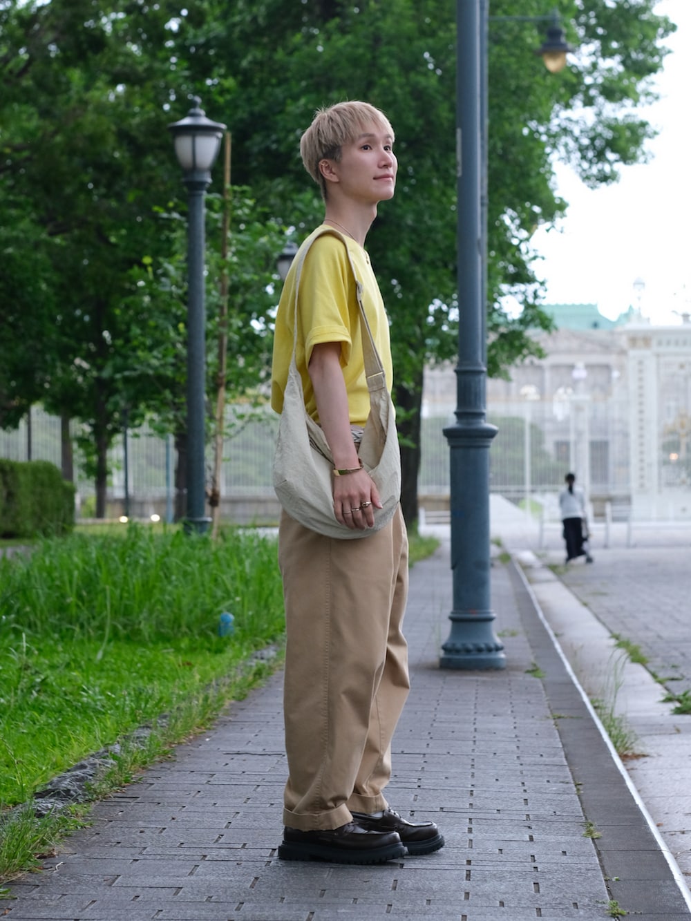 イエロー系のTシャツ/カットソー、ベージュ系のチノパンツ、ホワイト系のショルダーバッグを着用したメンズの夏コーディネートの3枚目の写真