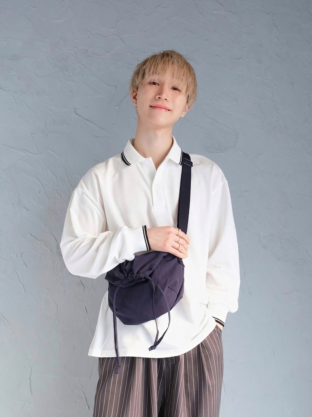 グレー系のその他パンツ、イエロー系のスニーカー、ホワイト系のポロシャツを着用したメンズの春コーディネートの2枚目の写真