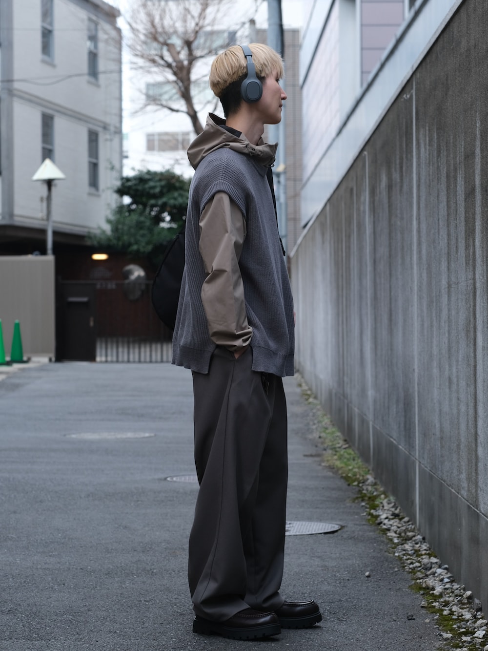 ブルー系のベスト、グレー系のスラックス、ブラウン系のローファーを着用したメンズの春コーディネートの2枚目の写真