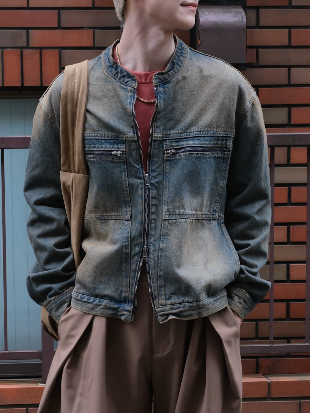 ブルー系のデニムジャケット、ブラウン系のスラックス、レッド系のニット/セーターを着用したメンズの秋コーディネートの4枚目の写真