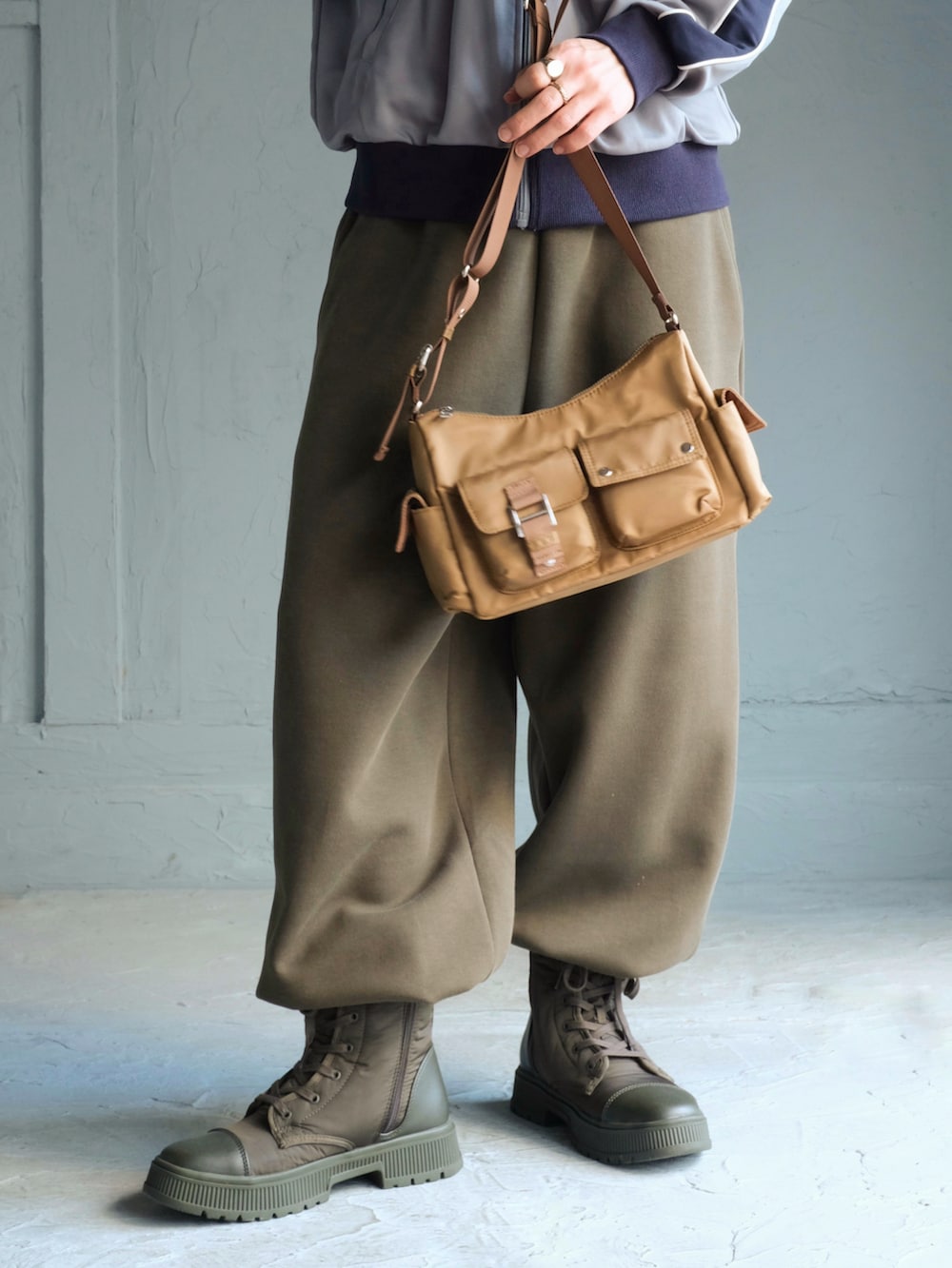 ブルー系のジャージ、ベージュ系のショルダーバッグ、グリーン系のスウェットパンツを着用したメンズの秋コーディネートの3枚目の写真