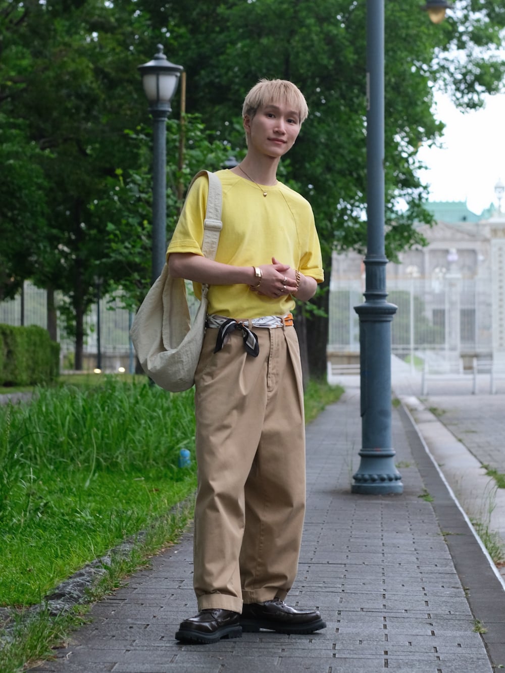 イエロー系のTシャツ/カットソー、ベージュ系のチノパンツ、ホワイト系のショルダーバッグを着用したメンズの夏コーディネートの5枚目の写真