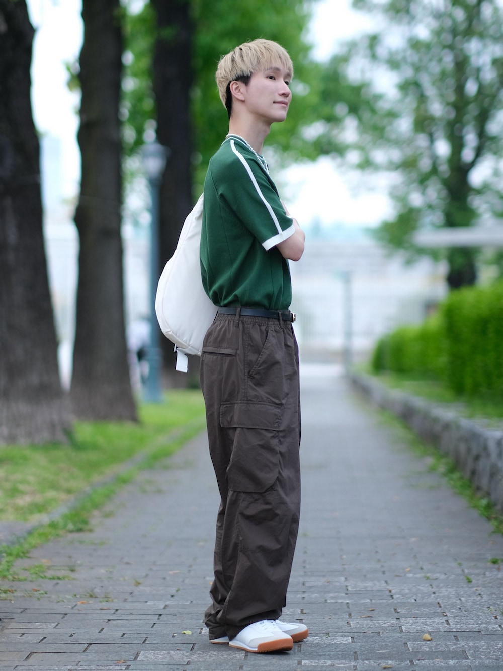 グリーン系のニット/セーター、ブラウン系のカーゴパンツ、ホワイト系のスニーカーを着用したメンズの夏コーディネートの2枚目の写真