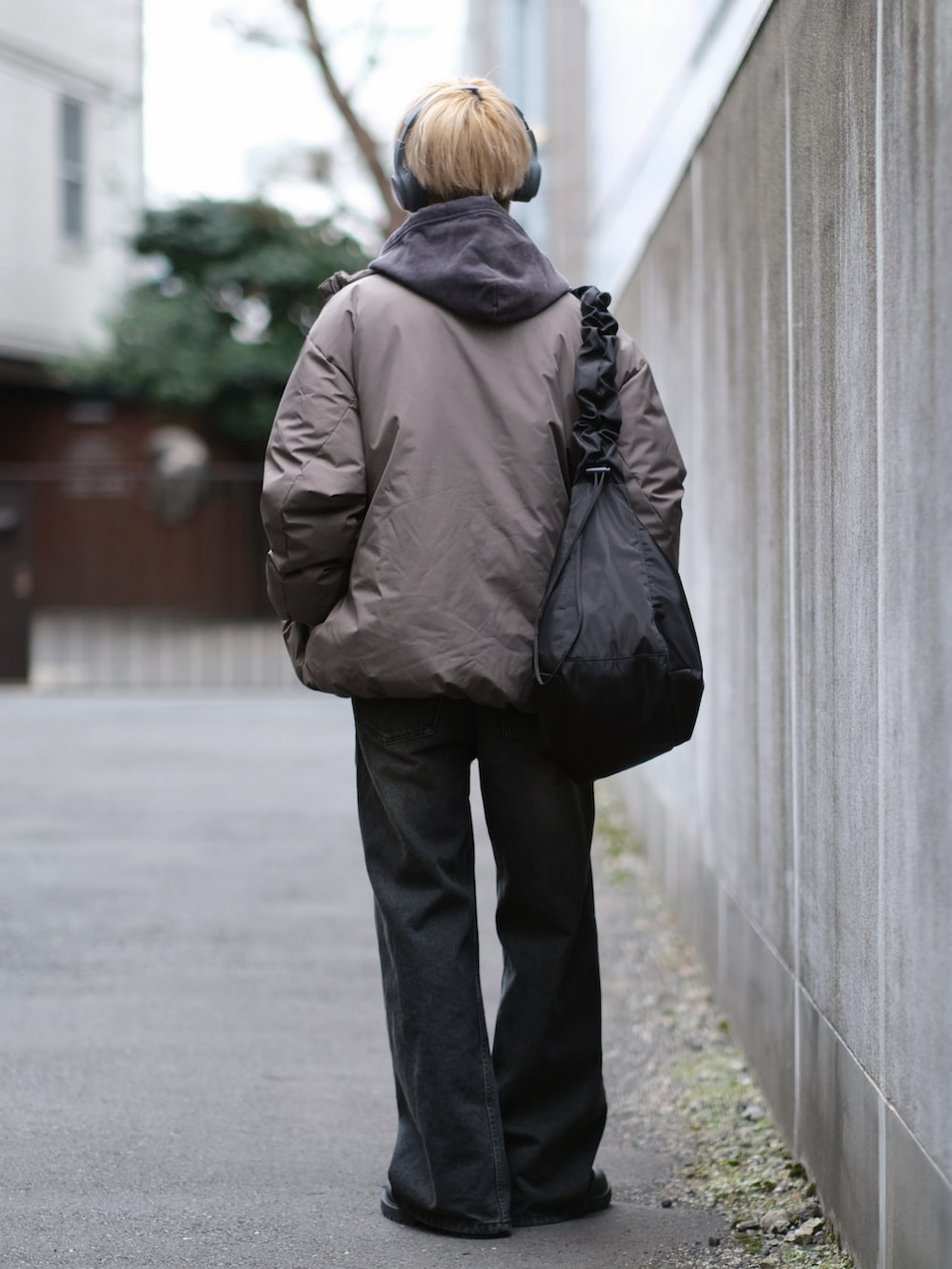 ブラウン系のダウンジャケット/コート、ブラック系のデニムパンツ、ブラック系のショルダーバッグを着用したメンズの冬コーディネートの5枚目の写真