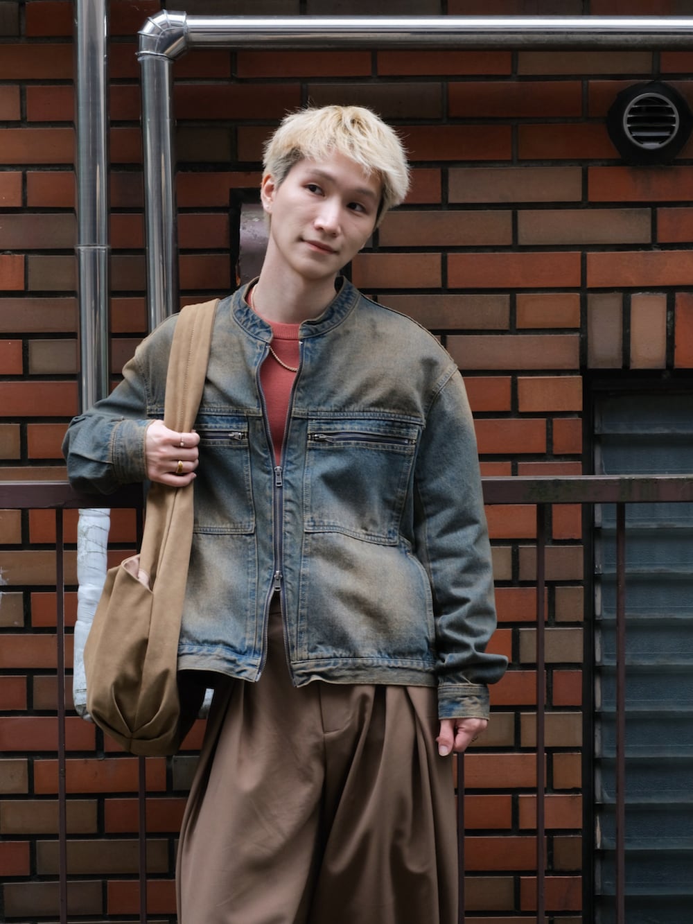 ブルー系のデニムジャケット、ブラウン系のスラックス、レッド系のニット/セーターを着用したメンズの秋コーディネートの2枚目の写真