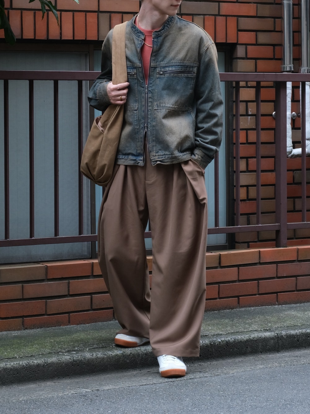 ブルー系のデニムジャケット、ブラウン系のスラックス、レッド系のニット/セーターを着用したメンズの秋コーディネートの3枚目の写真