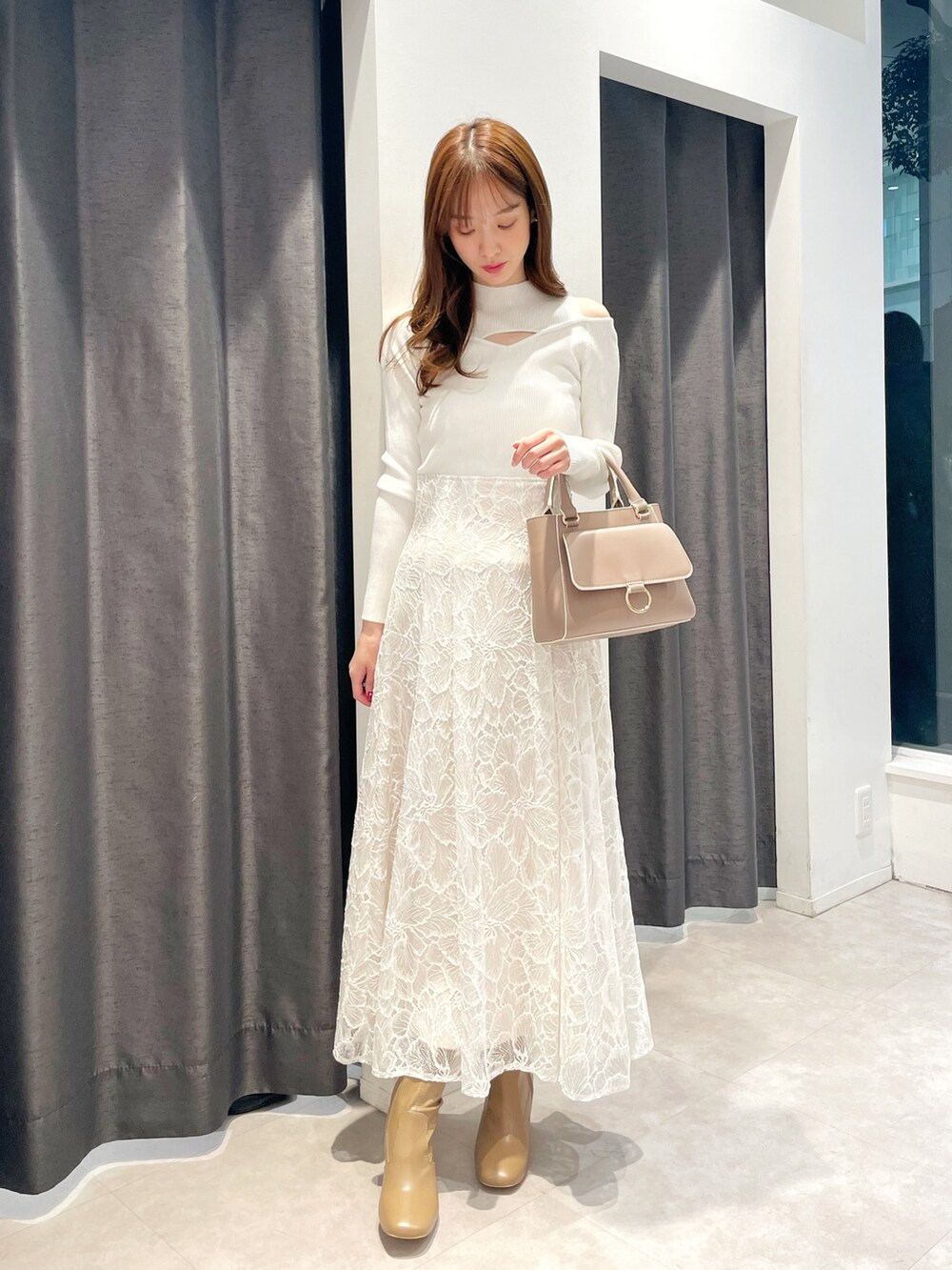 ホワイト系のスカート、ホワイト系のニット/セーター、ピンク系のトレンチコートを着用したレディースの冬コーディネートの2枚目の写真