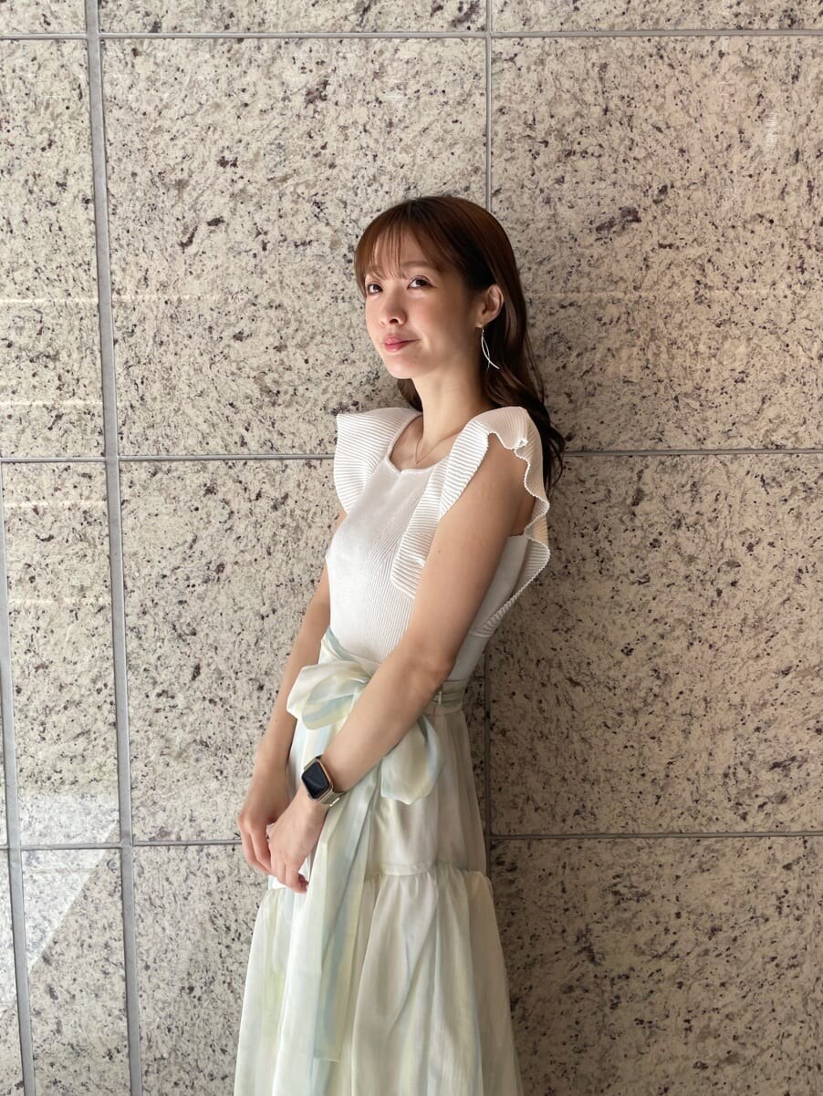 グリーン系のスカート、グリーン系のサンダル、ホワイト系のニット/セーターを着用したレディースの春コーディネートの6枚目の写真