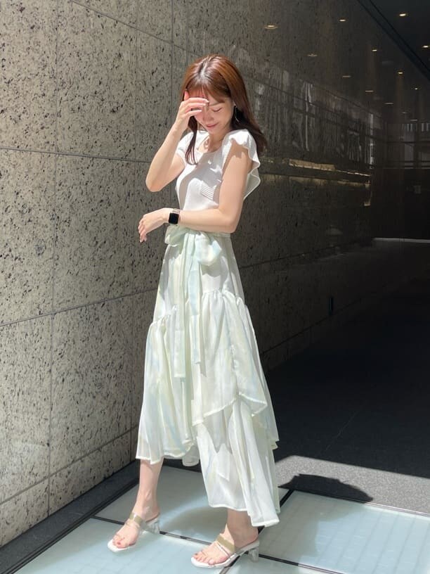 グリーン系のスカート、グリーン系のサンダル、ホワイト系のニット/セーターを着用したレディースの春コーディネートの5枚目の写真