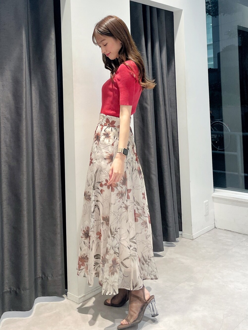 レッド系のニット/セーター、ピンク系のスカート、ブラウン系のブーツを着用したレディースの春コーディネートの2枚目の写真