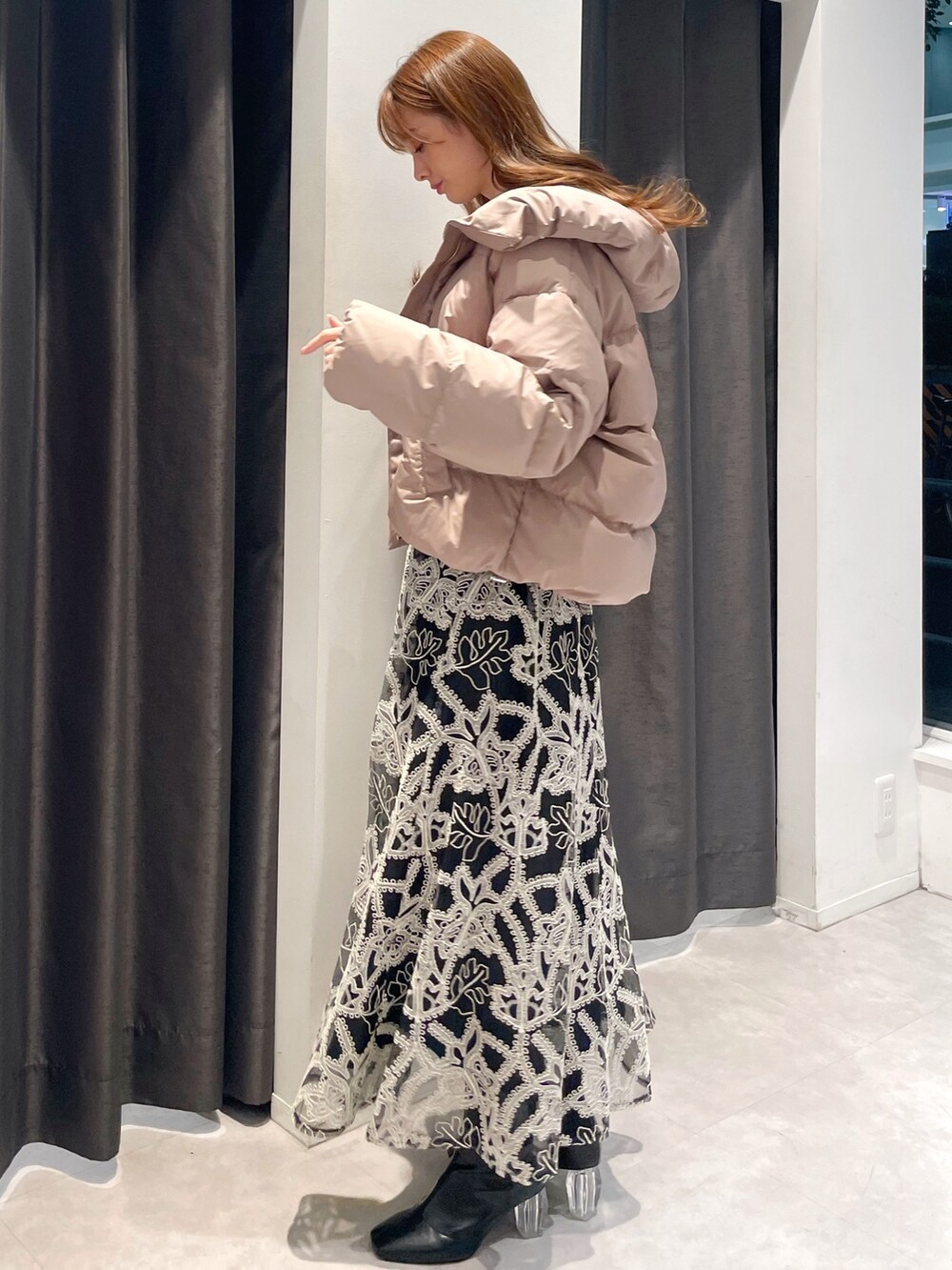 ブラウン系のダウンジャケット/コート、ホワイト系のニット/セーター、ブラック系のスカートを着用したレディースの冬コーディネートの2枚目の写真