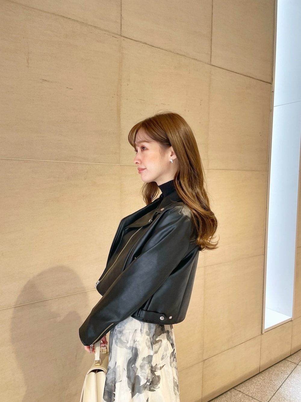 ブラック系のライダースジャケット、ブラック系のニット/セーター、ホワイト系のスカートを着用したレディースの冬コーディネートの6枚目の写真