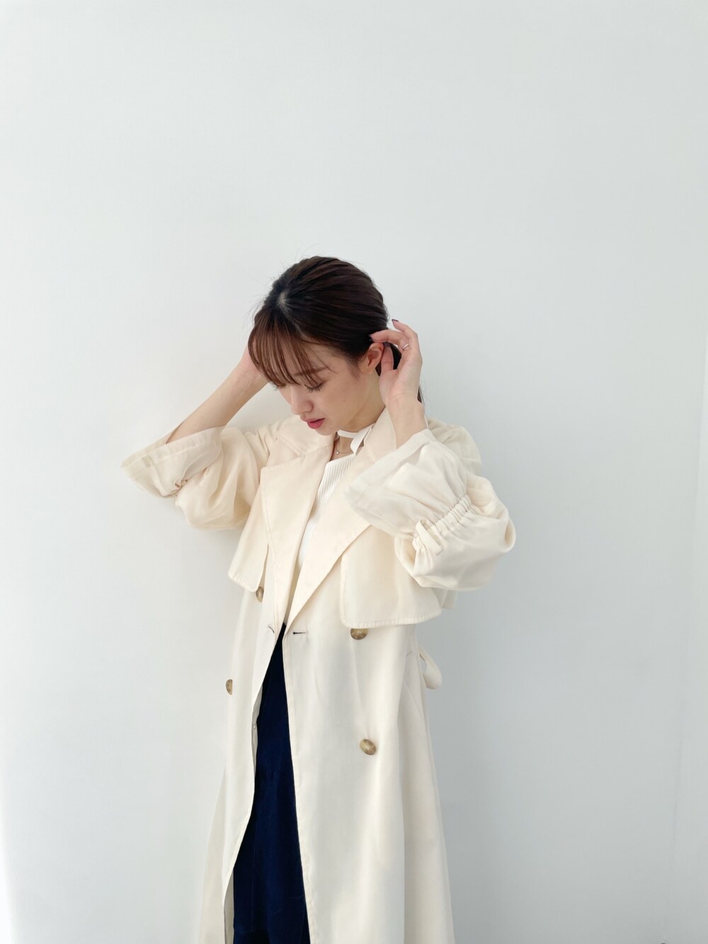 ホワイト系のトレンチコート、ブルー系のデニムスカート、ホワイト系のニット/セーターを着用したレディースの冬コーディネートの3枚目の写真