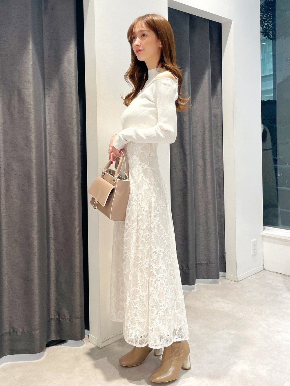 ホワイト系のスカート、ホワイト系のニット/セーター、ピンク系のトレンチコートを着用したレディースの冬コーディネートの3枚目の写真