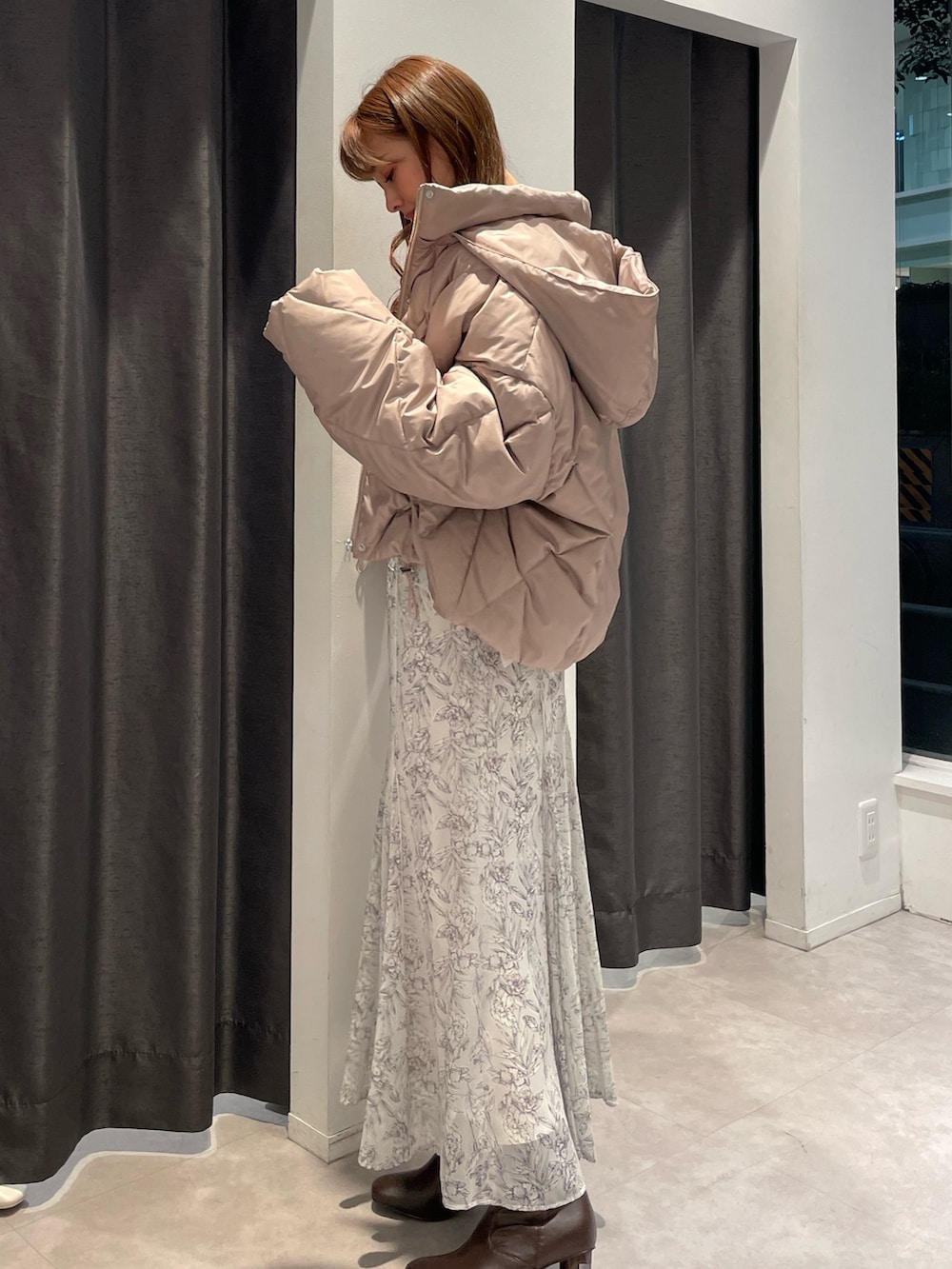 ベージュ系のダウンジャケット/コート、ホワイト系のニット/セーター、ホワイト系のスカートを着用したレディースの秋コーディネートの2枚目の写真