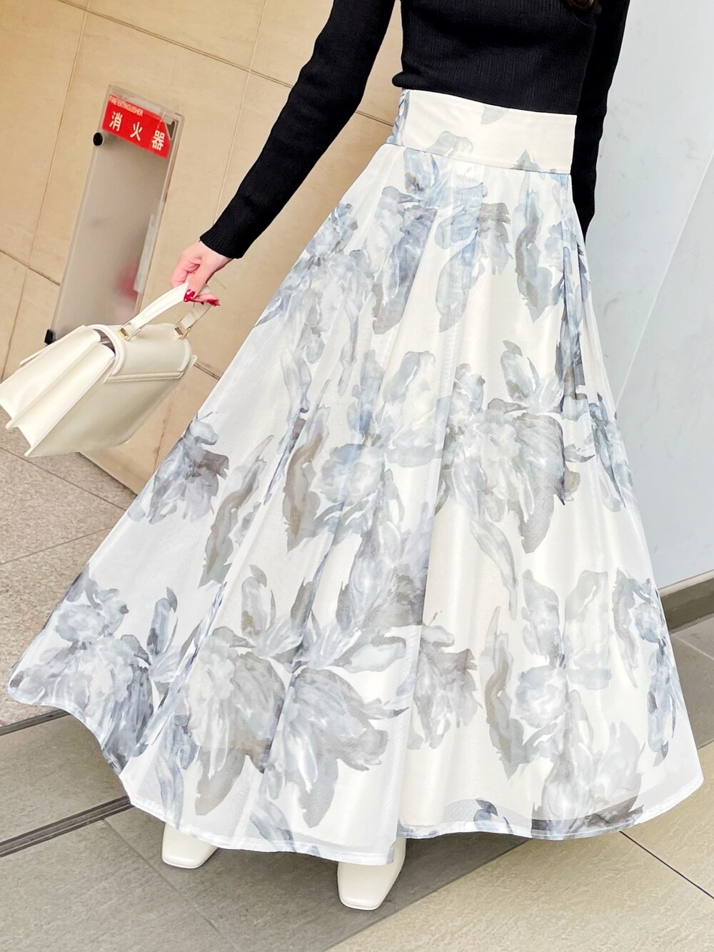 ブラック系のライダースジャケット、ブラック系のニット/セーター、ホワイト系のスカートを着用したレディースの冬コーディネートの9枚目の写真