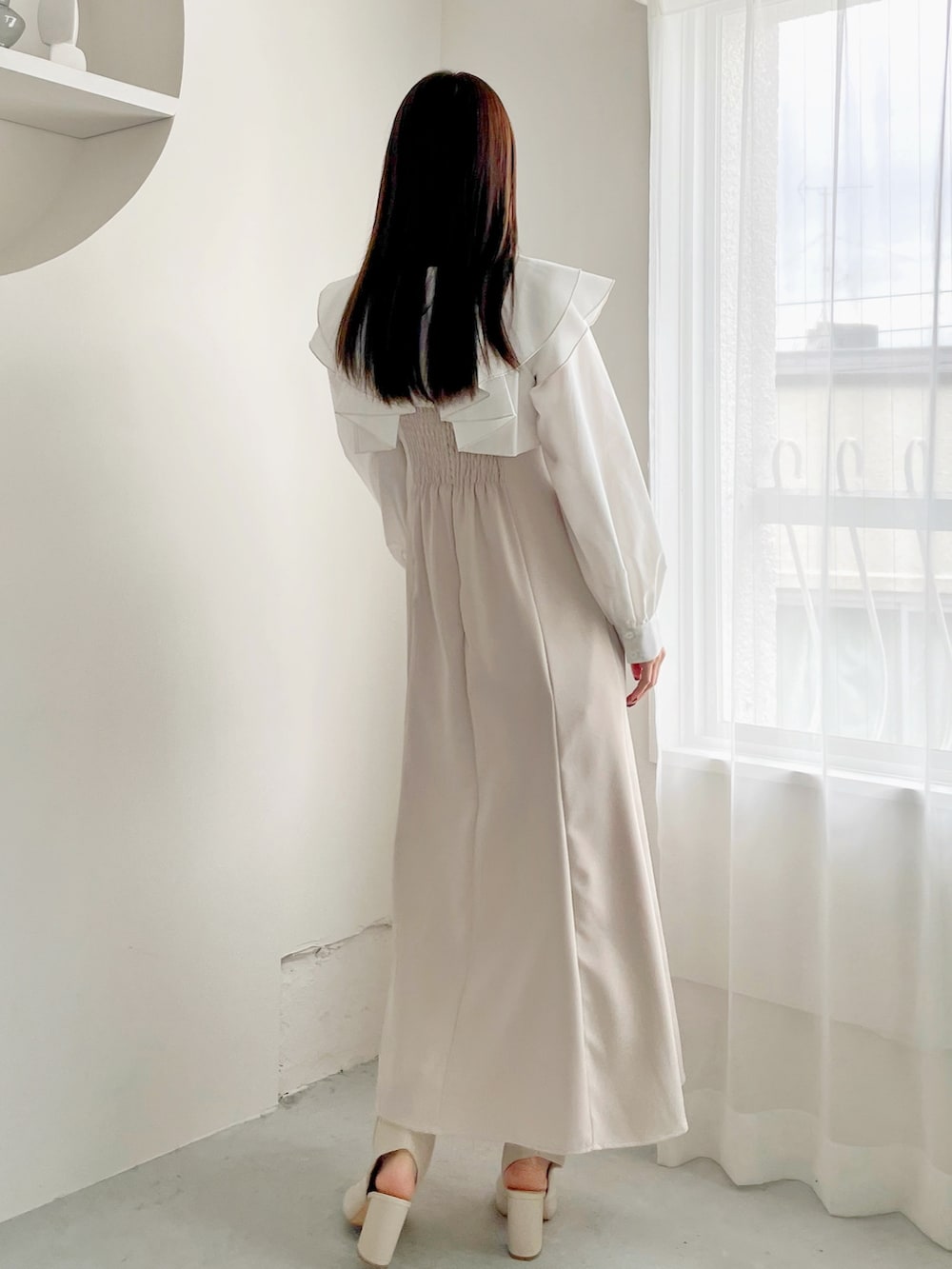 ベージュ系のワンピースを着用したレディースの冬コーディネートの2枚目の写真