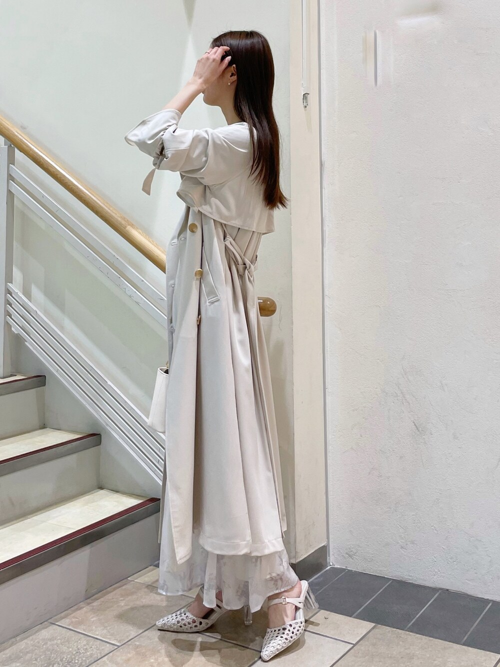 ホワイト系のトレンチコート、ブラック系のワンピース、ホワイト系のパンプスを着用したレディースの冬コーディネートの2枚目の写真