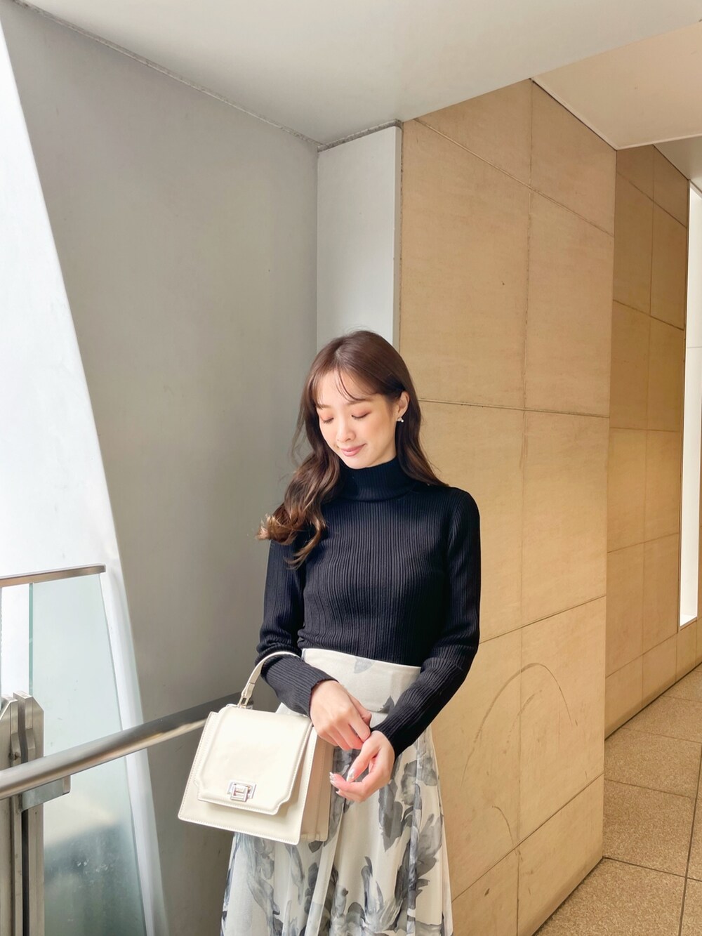 ブラック系のライダースジャケット、ブラック系のニット/セーター、ホワイト系のスカートを着用したレディースの冬コーディネートの8枚目の写真