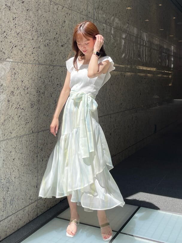 グリーン系のスカート、グリーン系のサンダル、ホワイト系のニット/セーターを着用したレディースの春コーディネートの2枚目の写真