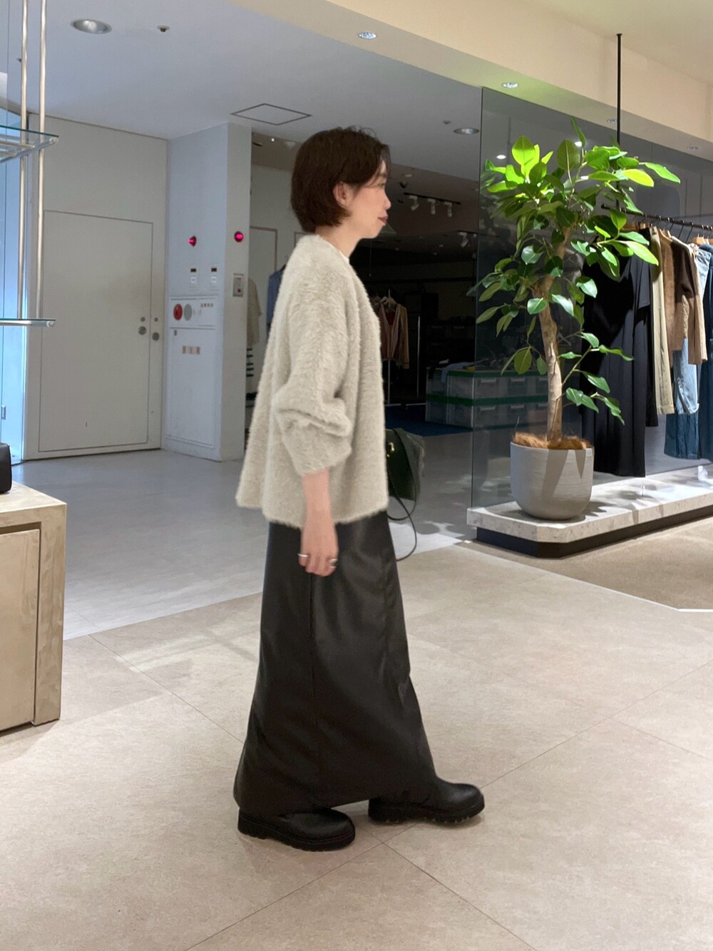 ベージュ系のカーディガン/ボレロ、ブラック系のスカート、ホワイト系のTシャツ/カットソーを着用したレディースの秋コーディネートの2枚目の写真