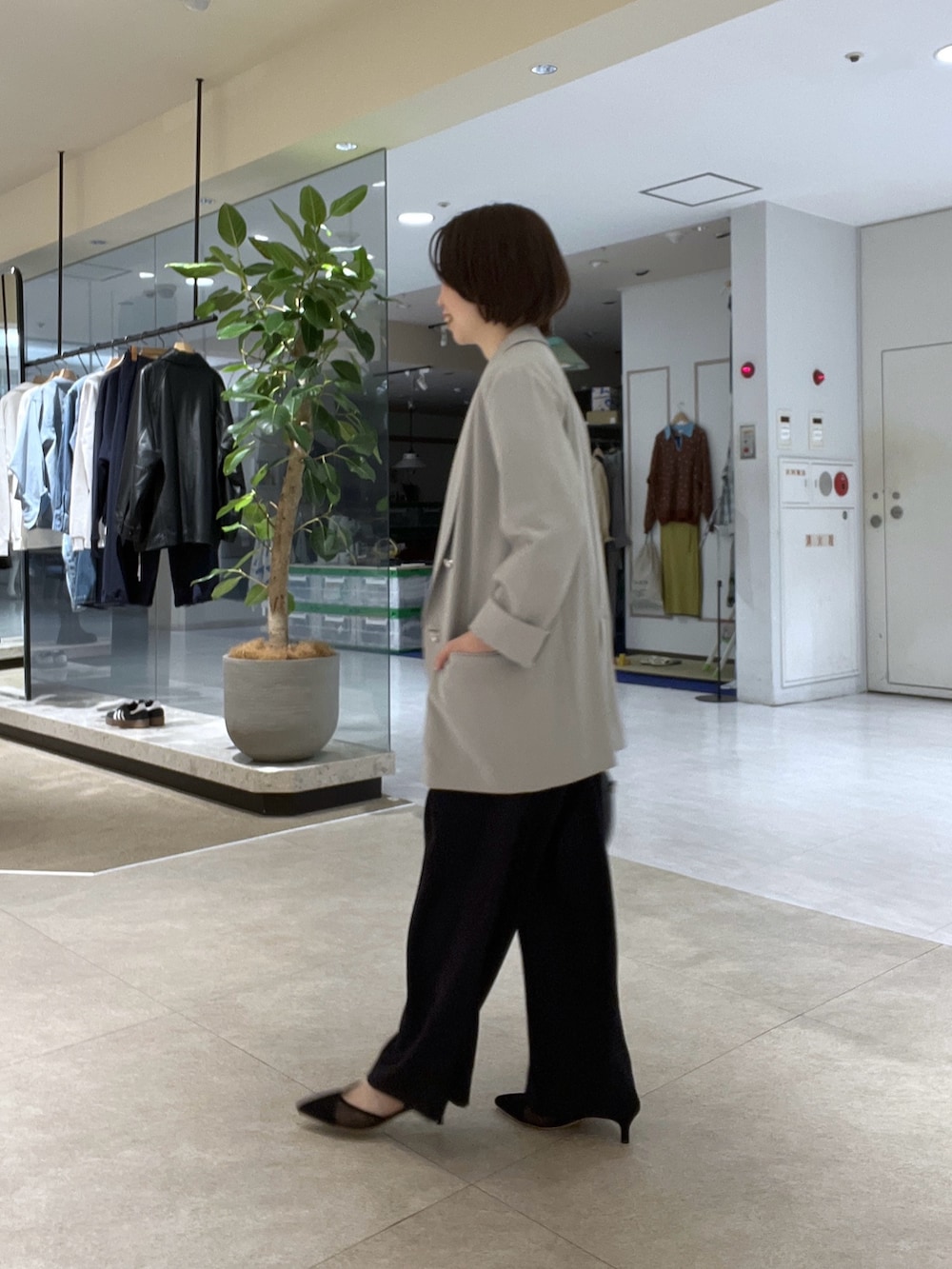 グレー系のテーラードジャケット、ブルー系のスラックス、ブラック系のボストンバッグを着用したレディースの冬コーディネートの2枚目の写真