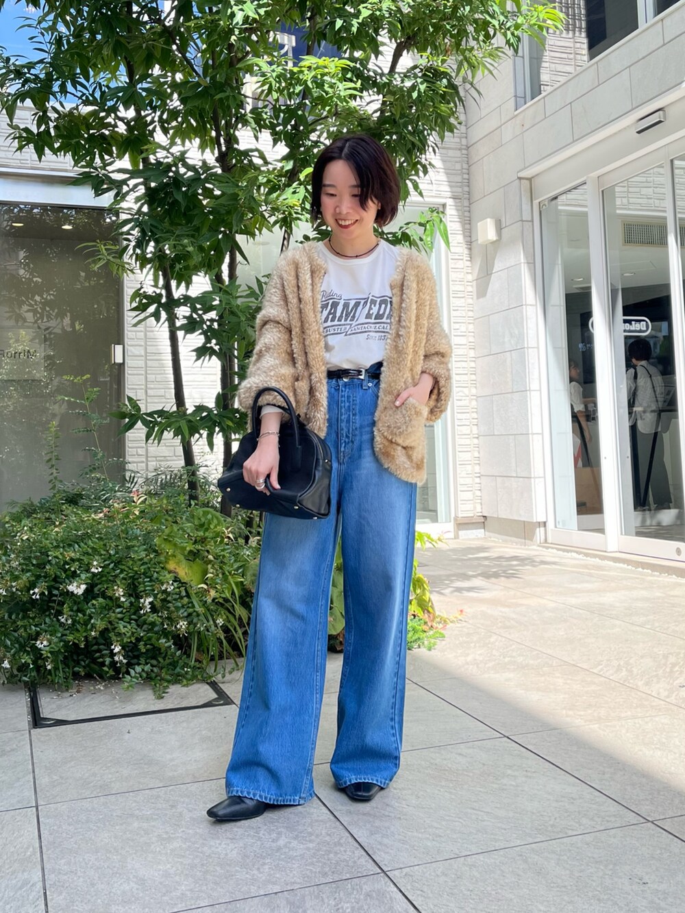 ブルー系のデニムパンツ、ホワイト系のTシャツ/カットソー、ブラック系のボストンバッグを着用したレディースの秋コーディネートの3枚目の写真