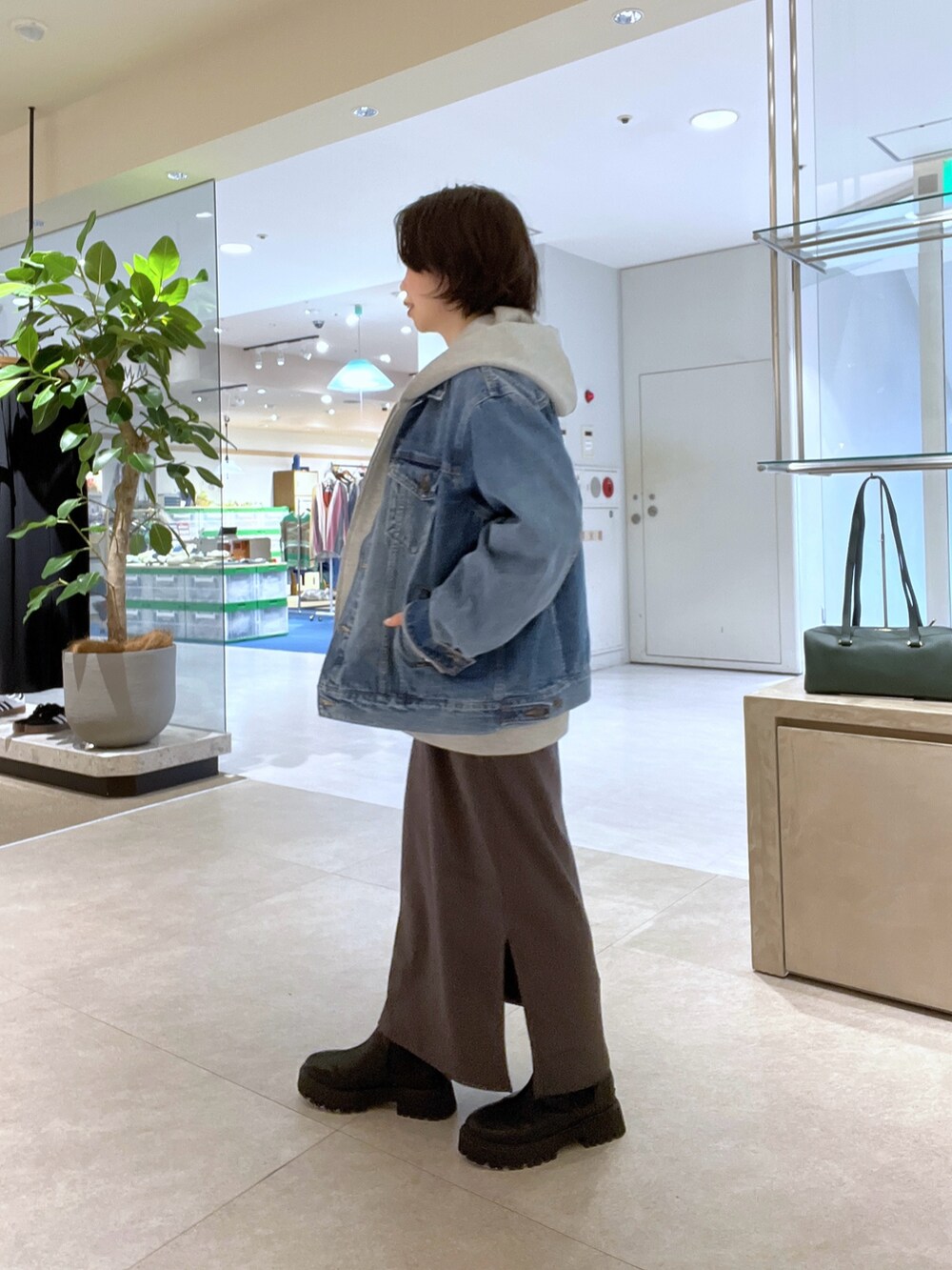 ブラウン系のワンピース、ブラック系のショルダーバッグ、ブラック系のブーツを着用したレディースの秋コーディネートの2枚目の写真