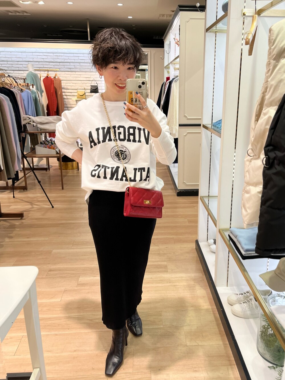 ホワイト系のノーカラーコート、ホワイト系のTシャツ/カットソー、ブラック系のスカートを着用したレディースの冬コーディネートの2枚目の写真
