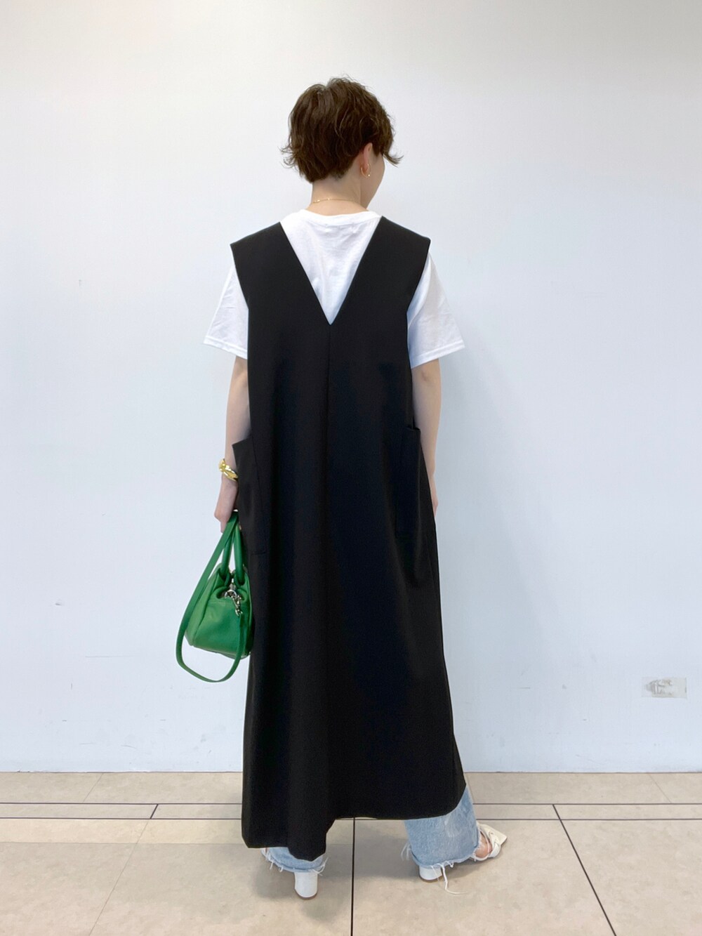 ブルー系のデニムパンツ、ブラック系のワンピース、ホワイト系のTシャツ/カットソーを着用したレディースの春コーディネートの3枚目の写真