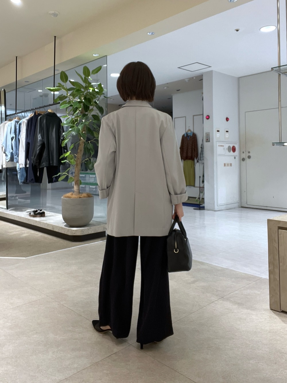 グレー系のテーラードジャケット、ブルー系のスラックス、ブラック系のボストンバッグを着用したレディースの冬コーディネートの3枚目の写真