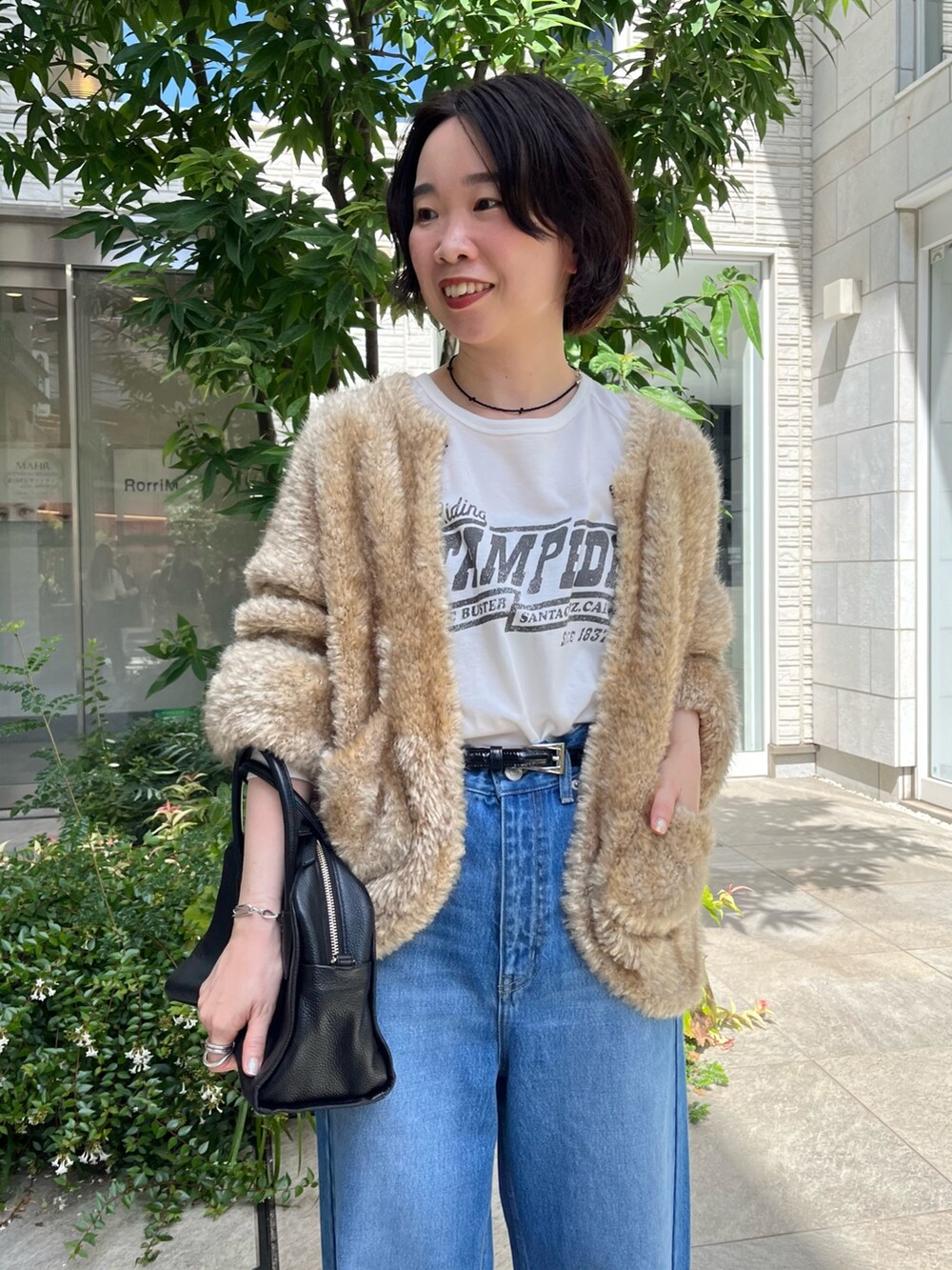 ブルー系のデニムパンツ、ホワイト系のTシャツ/カットソー、ブラック系のボストンバッグを着用したレディースの秋コーディネートの4枚目の写真