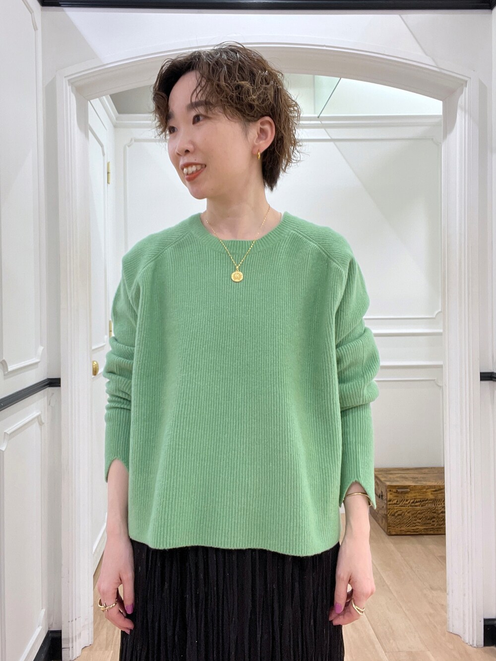 ブラック系のスカート、グリーン系のニット/セーター、ブラック系のショルダーバッグを着用したレディースの冬コーディネートの3枚目の写真