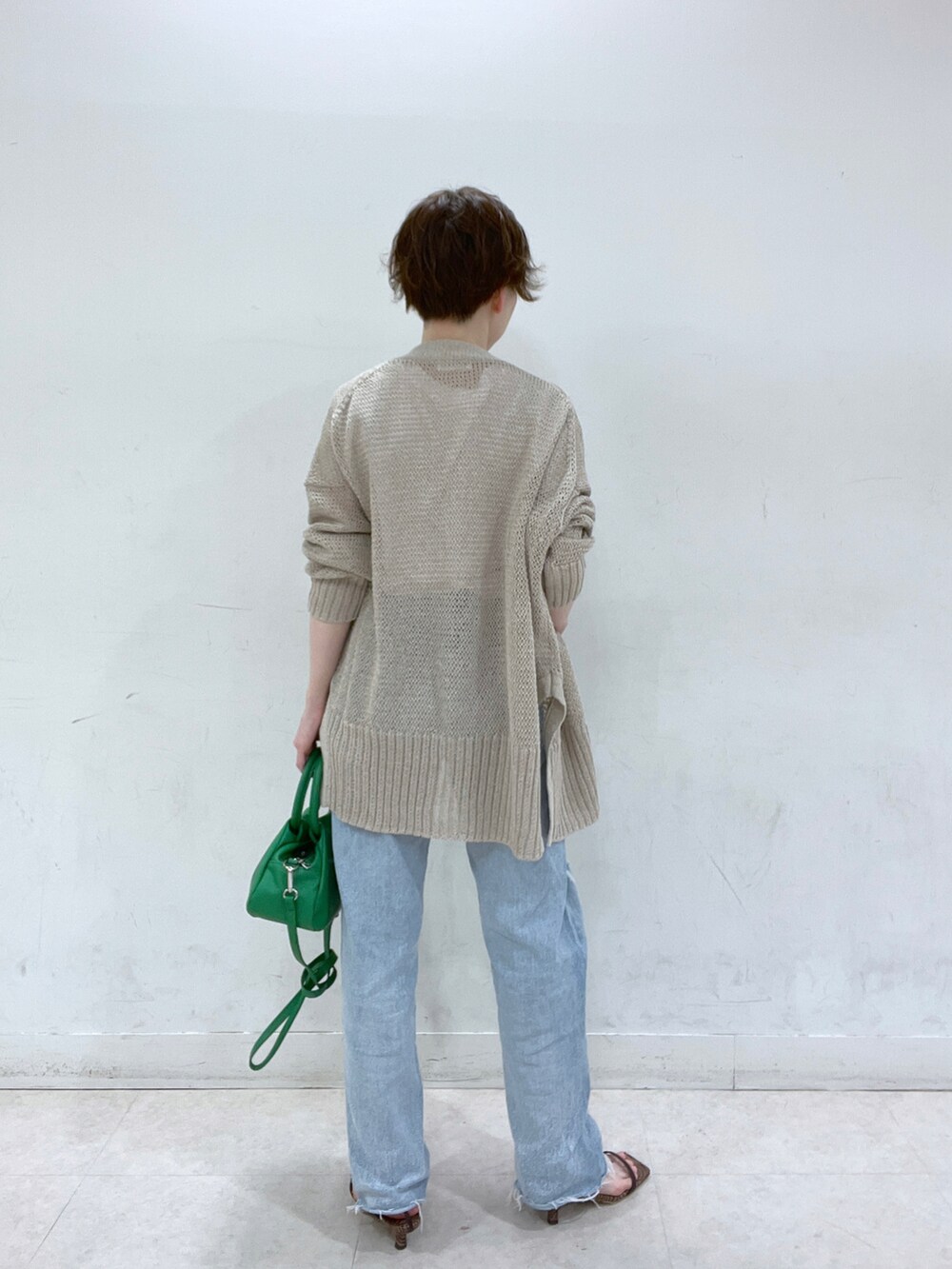 ブルー系のデニムパンツ、ベージュ系のカーディガン/ボレロ、ホワイト系のTシャツ/カットソーを着用したレディースの春コーディネートの3枚目の写真