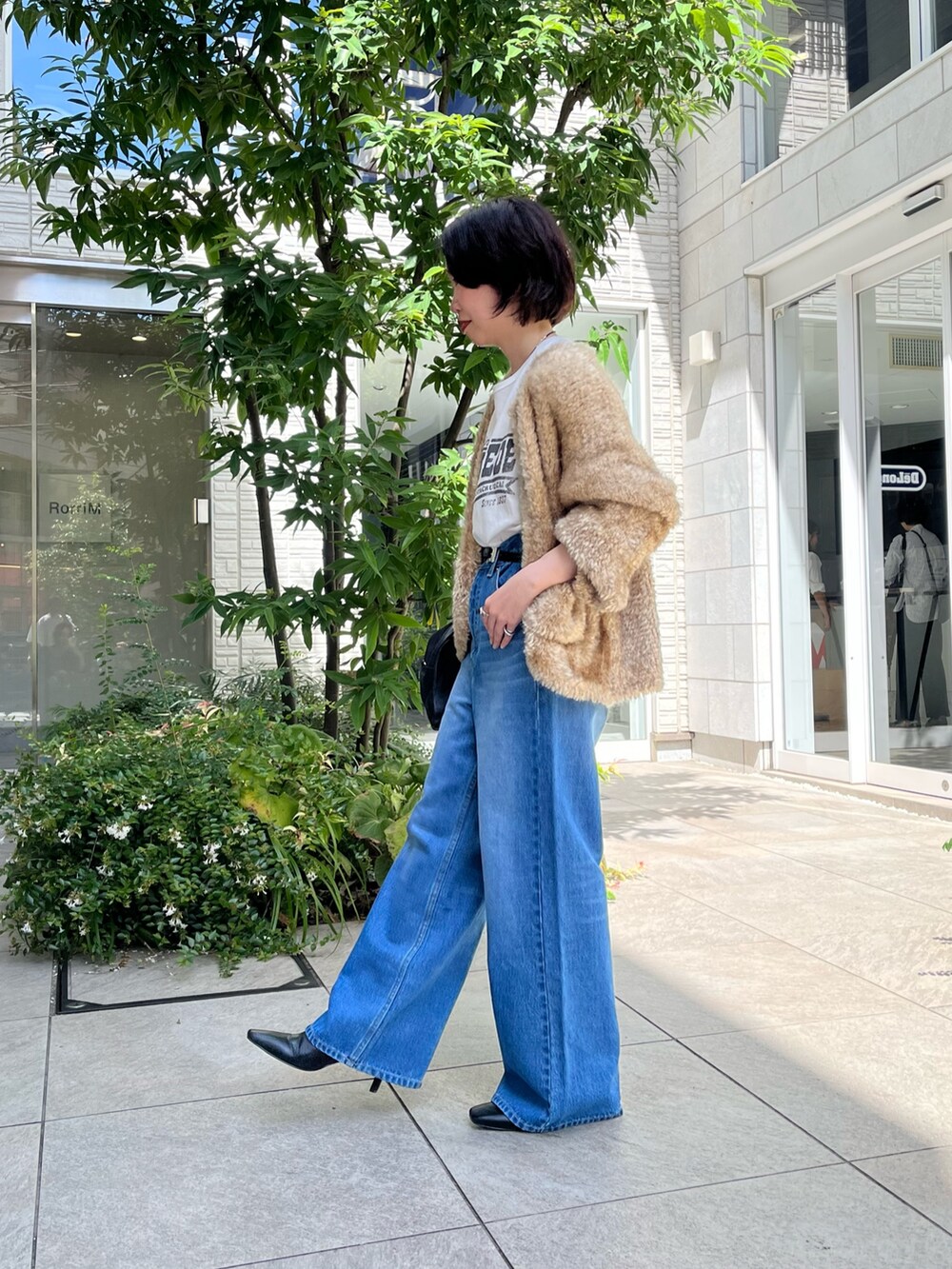 ブルー系のデニムパンツ、ホワイト系のTシャツ/カットソー、ブラック系のボストンバッグを着用したレディースの秋コーディネートの2枚目の写真