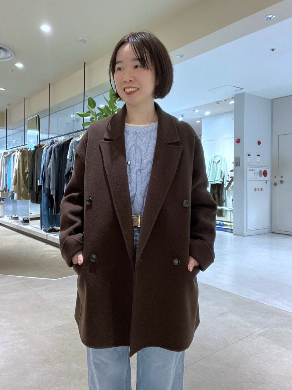 ブルー系のデニムパンツ、ブラウン系のボストンバッグ、ブラウン系のブーツを着用したレディースの秋コーディネートの4枚目の写真